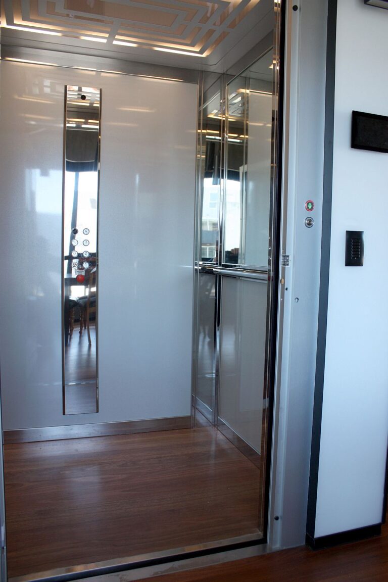 Inside the E1 lift with a mirror strip on the wall and a glass door