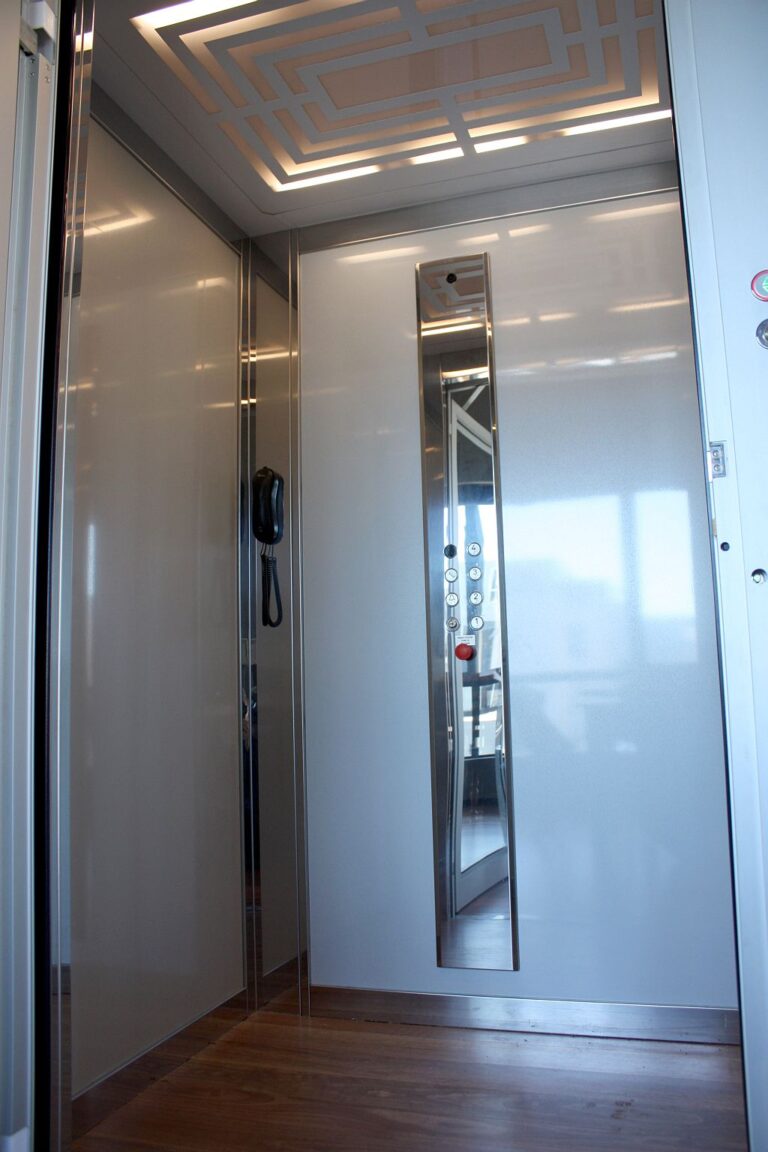Inside the E1 lift with white gloss panels, a mirror strip and a patterned ceiling light