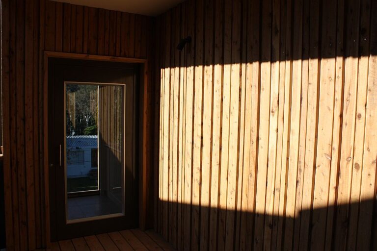 Timber clad wall and glass door with stripes of sunlight in Fairfield