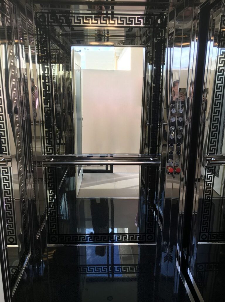 Inside the E1 Classica cabin with polished stainless steel walls, Greek key etching and a black Star floor