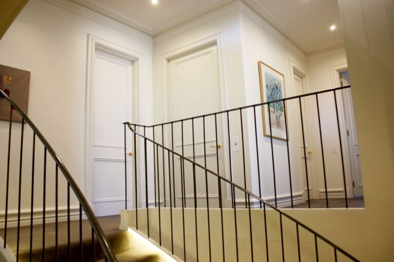 Landing with a black balustrade, white panelled doors and a framed artwork in Sydney Harbour