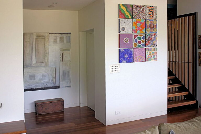 Hallway with colourful wall art, a timber staircase and a bench near the lift