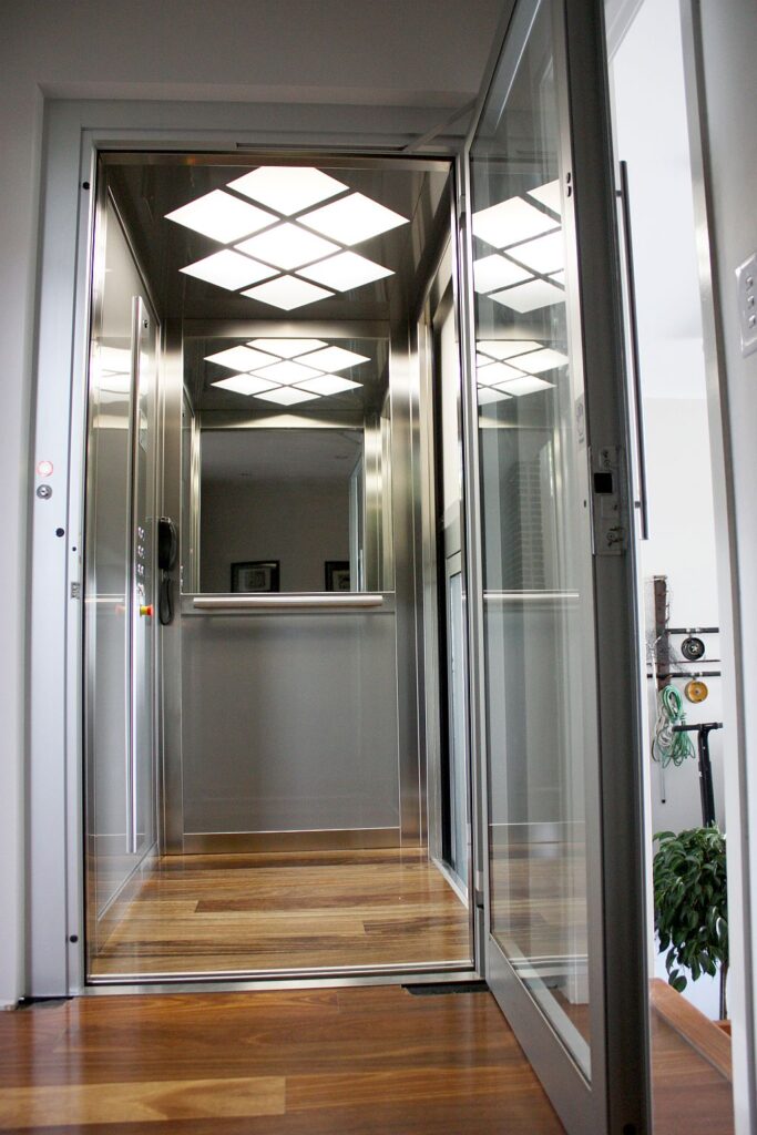 Looking into the three-level lift cabin with diamond pattern ceiling lights, stainless steel walls and a timber floor