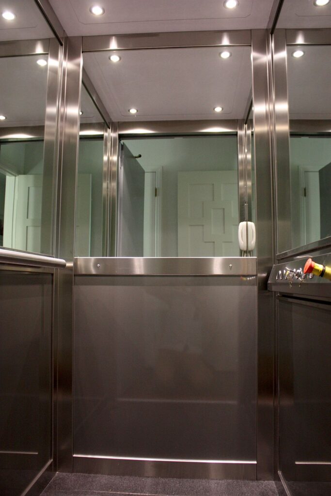Inside the two-level ElfoLift cabin: brushed stainless steel panels and profiles, half-height mirrors and white LED downlights