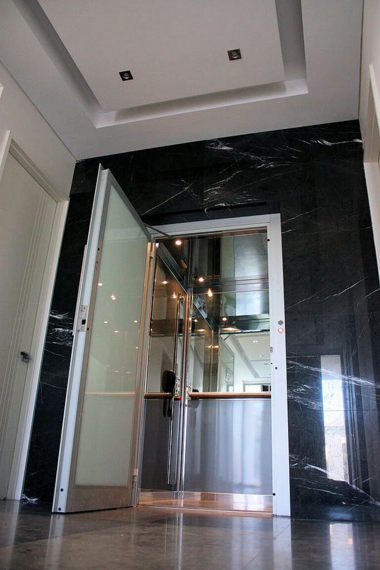 Glass home lift door set into a black marble feature wall in a City Beach home