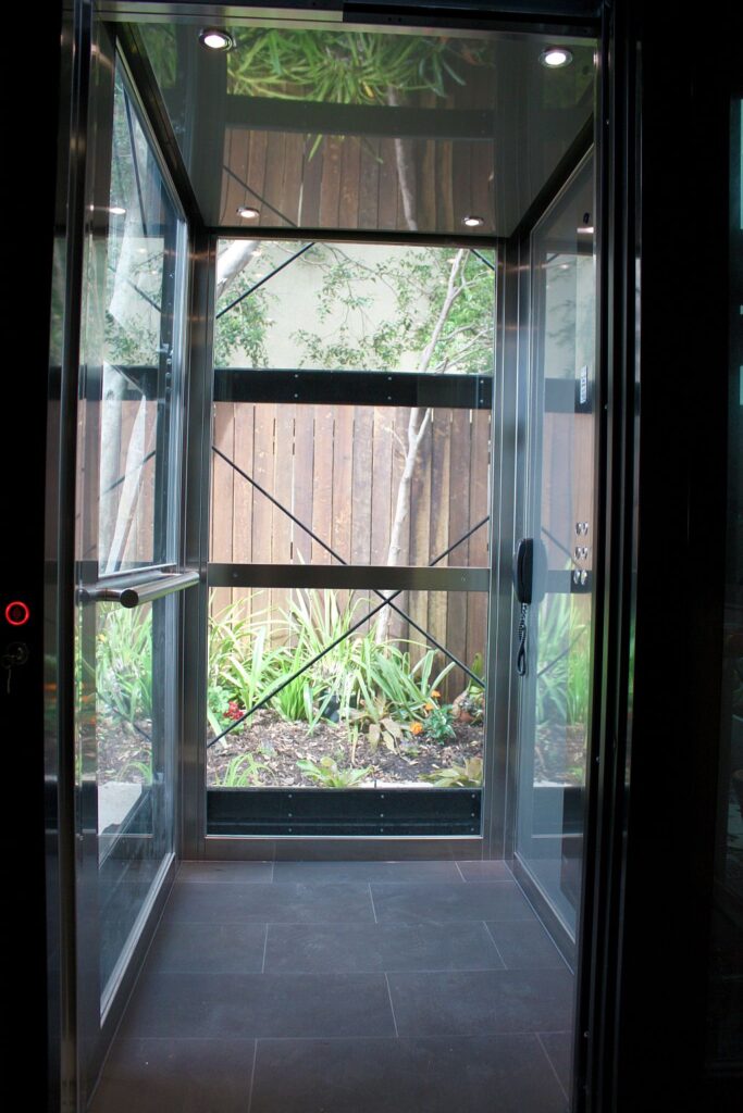 Inside the glass E2 cabin with stainless steel framing, slate-look floor tiles and a view of the garden