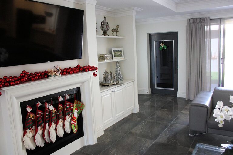 Living room with a fireplace hung with stockings and a dark framed lift door beyond, Coogee
