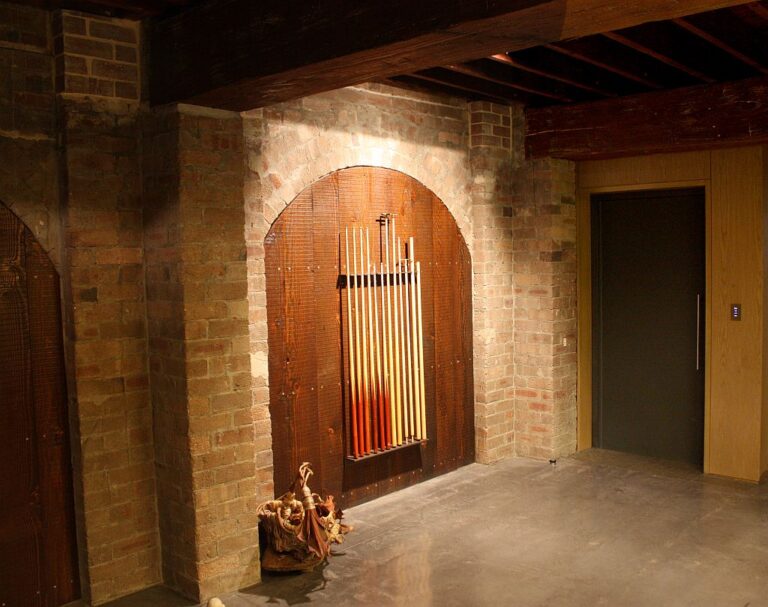 Exposed brick wall with an arched timber door and a lift door in a converted warehouse