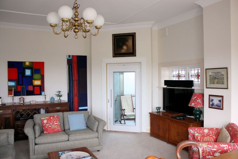 Living room with a chandelier and a white lift door with a glass panel beside the television