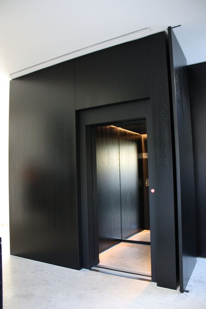 Black timber-panelled ElfoLift 2 with an open door and glowing LED cabin in a Toorak home
