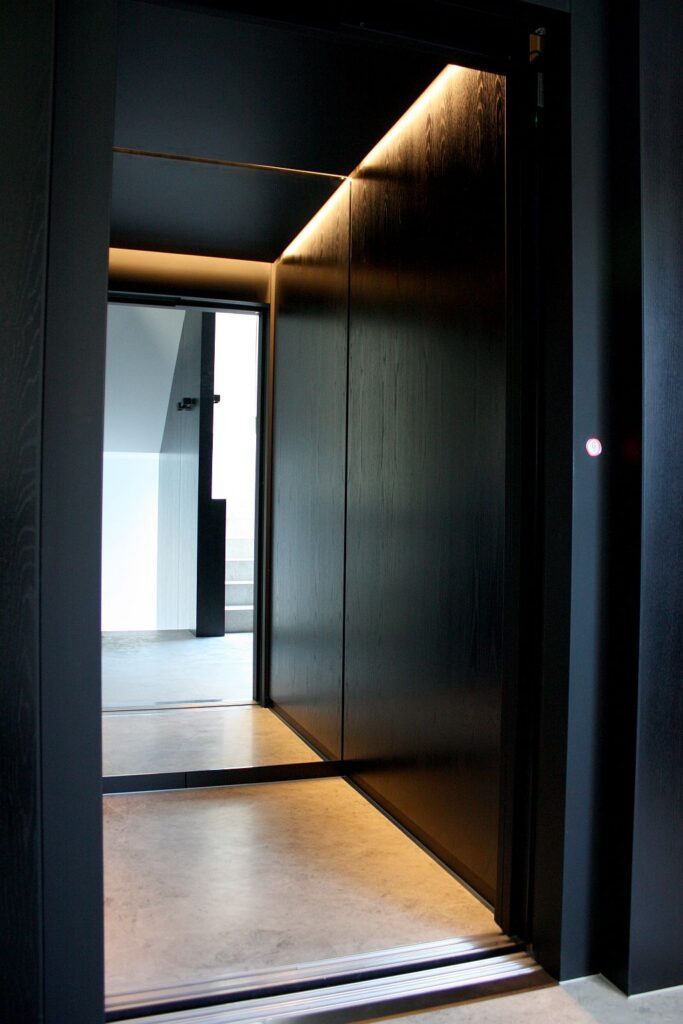 Inside the black timber-lined ElfoLift 2 cabin with LED lighting and a tiled floor