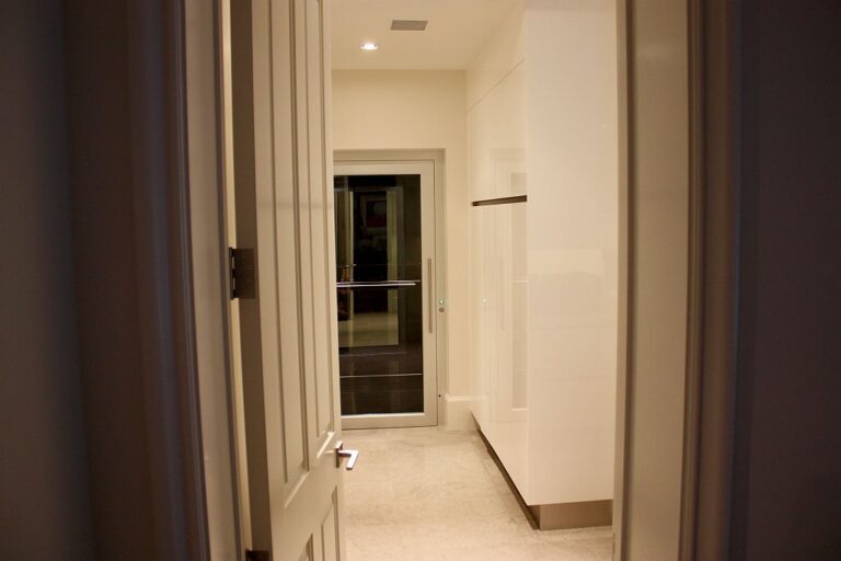 Hallway with a lift door at the end beside a curtain and white cabinetry in Noosaville