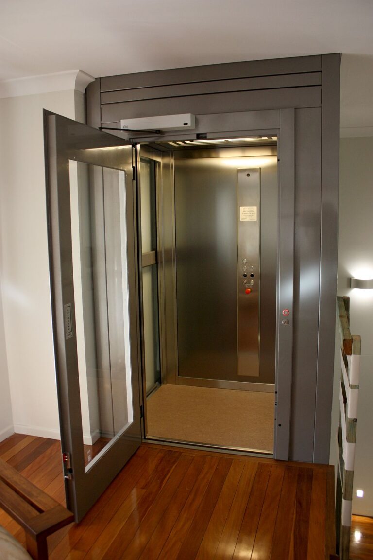 Open ElfoLift door with a grey frame and a stainless steel car on a timber floor