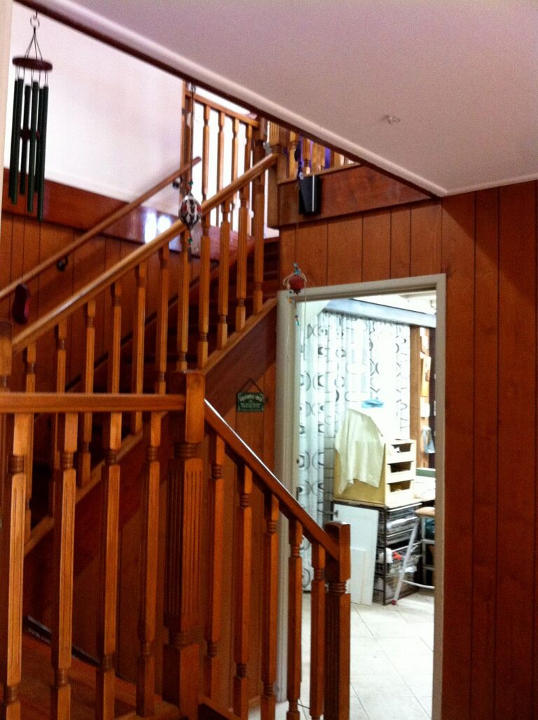 Timber staircase and balustrade beside timber panelled walls in the existing home