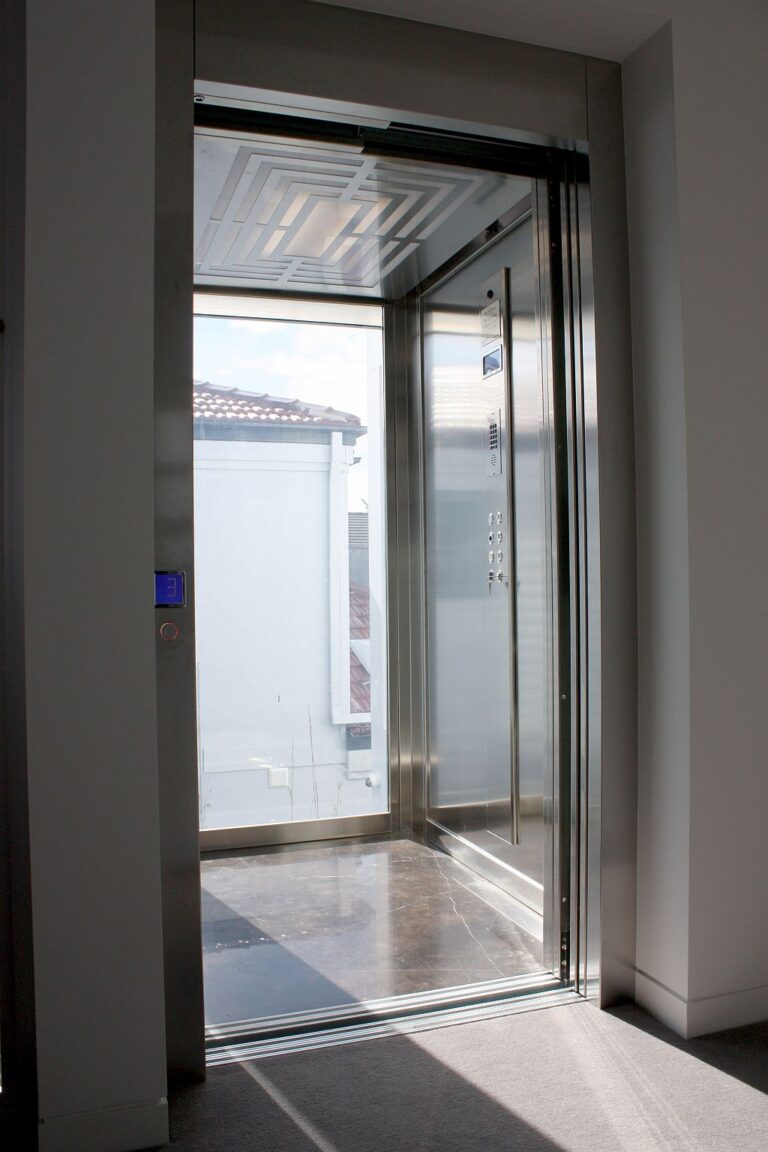 Open lift door on an upper level showing a Labirint pattern ceiling, stainless steel panel and digital position indicator