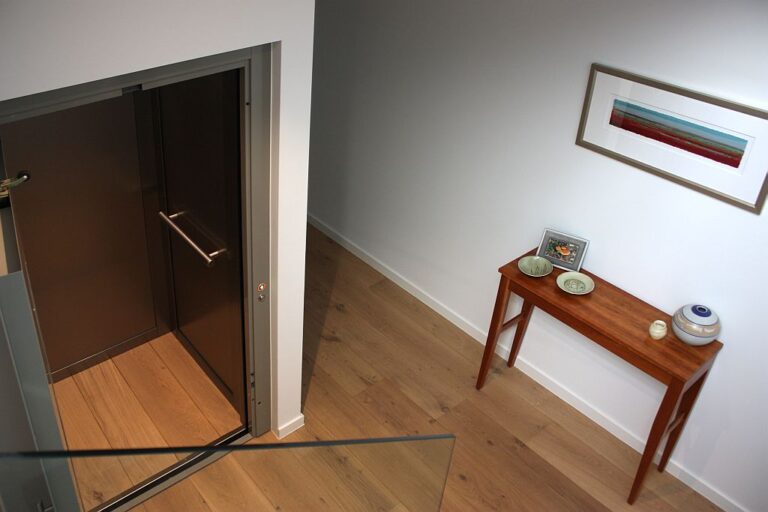 Open ElfoLift door in a hallway with a timber side table and framed artwork