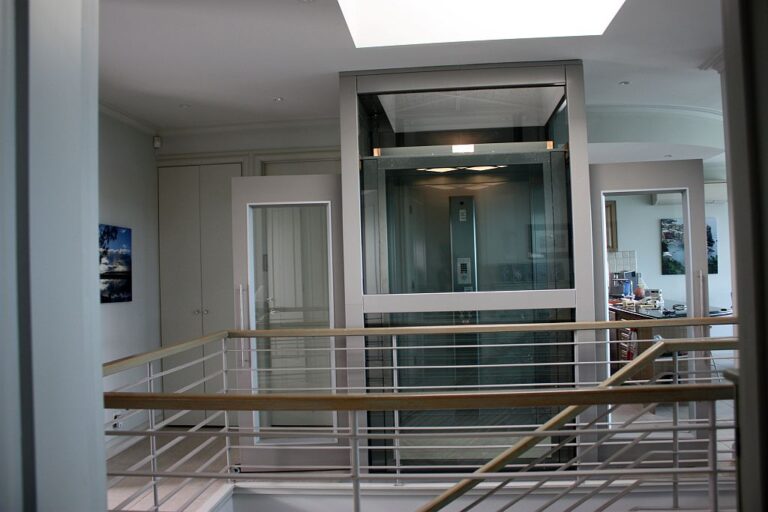 Glass fronted lift seen above a steel rail balustrade in a bright home in Black Rock