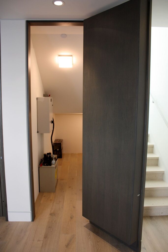 Dark door swung open to the small below-stair room where the lift machine equipment is hidden