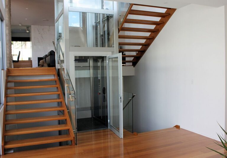 Glass home lift beside a timber staircase with open treads in Ashgrove