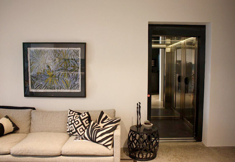 Living area with a sofa and framed artwork beside a dark lift door