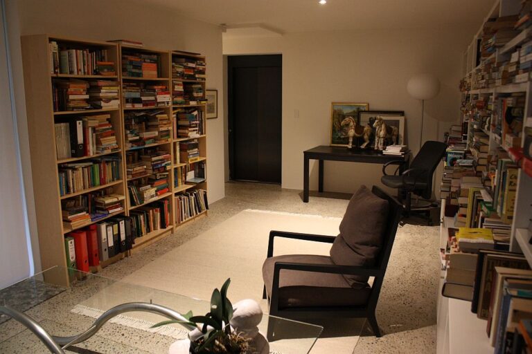 Home library with bookshelves, an armchair and a dark lift door at the back