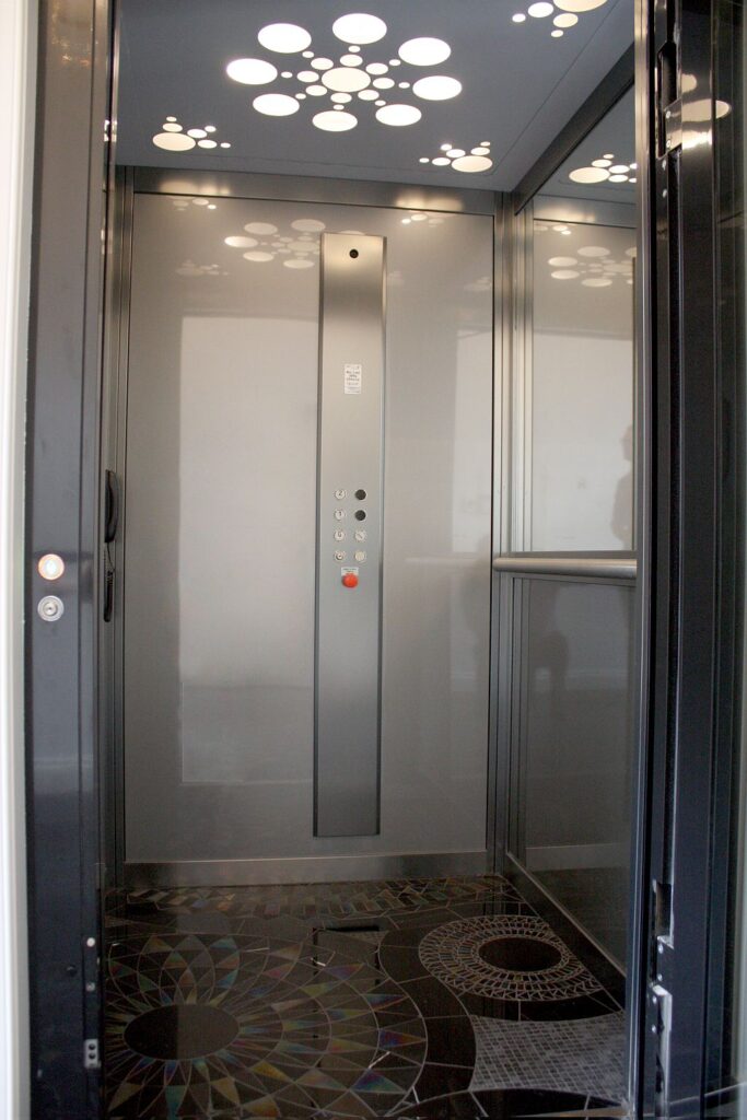 Inside the three-level ElfoLift cabin with a flower-pattern LED ceiling light, stainless steel panel and mosaic tiled floor