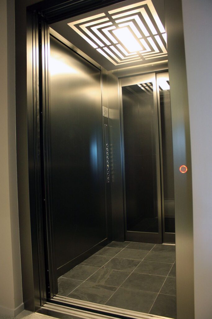 Inside the dark metal home lift cabin with a patterned ceiling light and slate floor