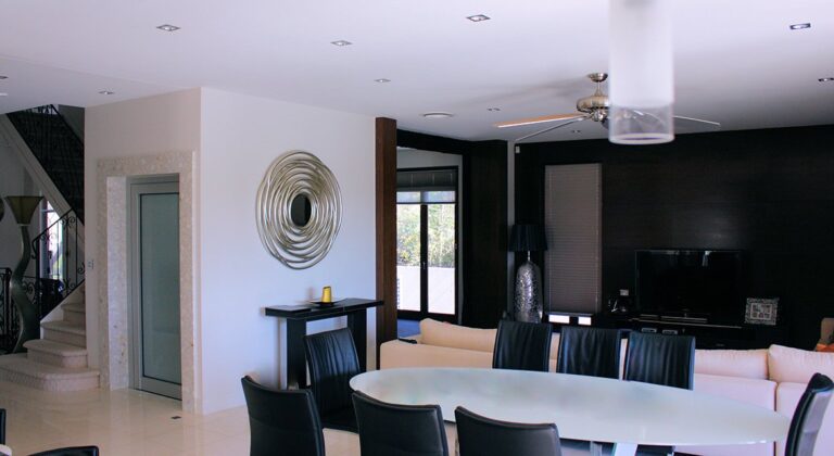 Dining and lounge area with a wall mirror and a glass door lift in Sanctuary Cove