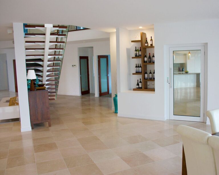 Tiled living area with open stairs, wine shelves and a glass lift door, Isle of Capri
