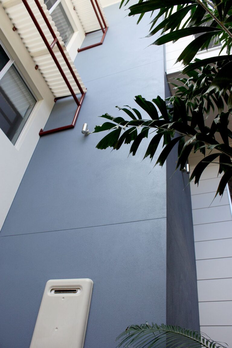 Looking up the grey rendered exterior wall of the shaft built into the side of the Shelly Beach home