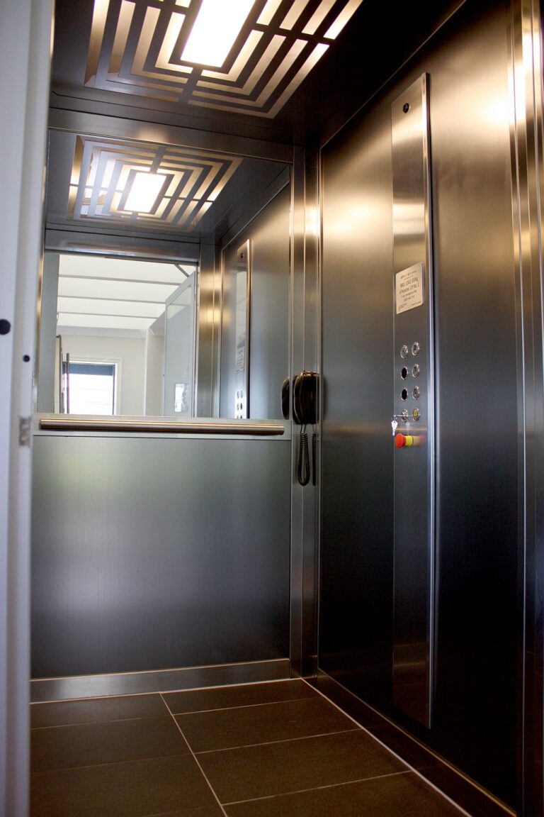 Inside the ElfoLift with dark steel panels, a button panel and patterned ceiling lights