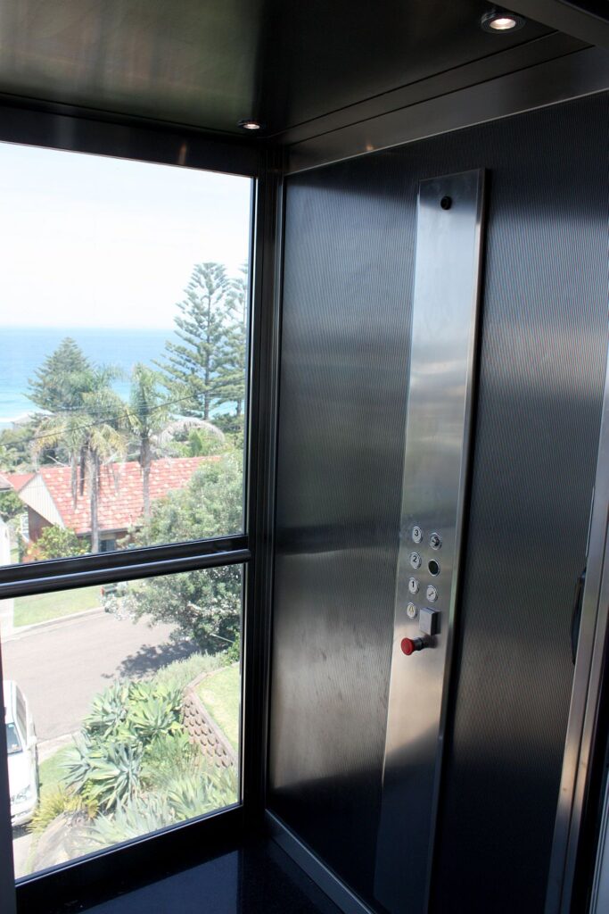 Inside the Inox Striped Blue stainless steel cabin with the control panel and a glass wall looking out to the ocean