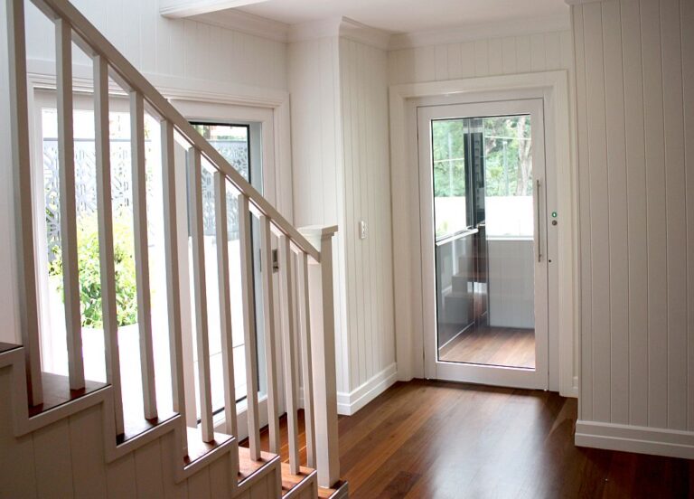 Timber staircase with white balusters beside a glass door opening to a verandah