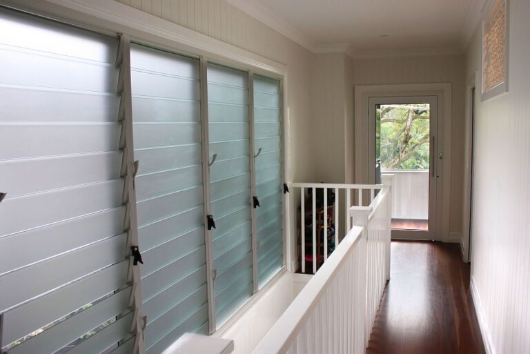 Hallway with louvre windows, white balustrade and polished timber floor