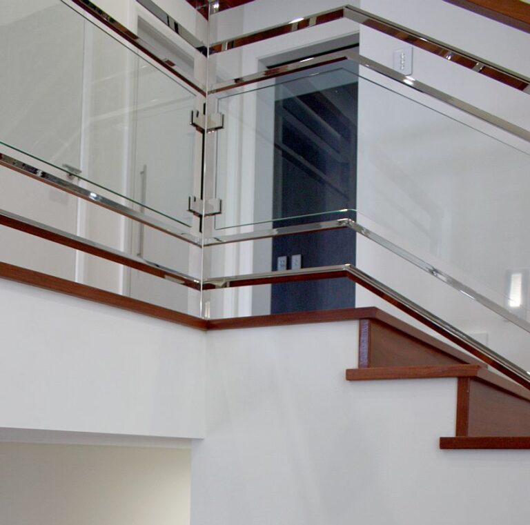 Glass balustrade with a timber handrail above a staircase and a dark doorway