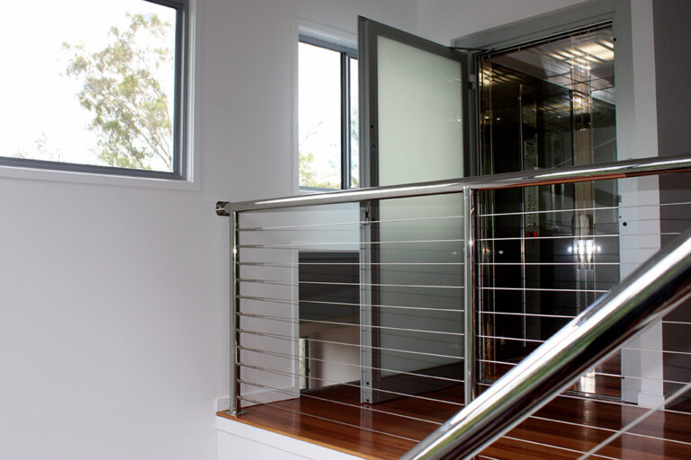 Open lift door beside a stainless steel cable balustrade on a landing