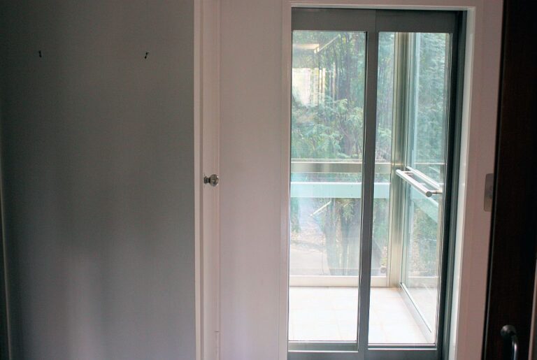 Sliding glass lift doors on a landing, showing trees through the cabin