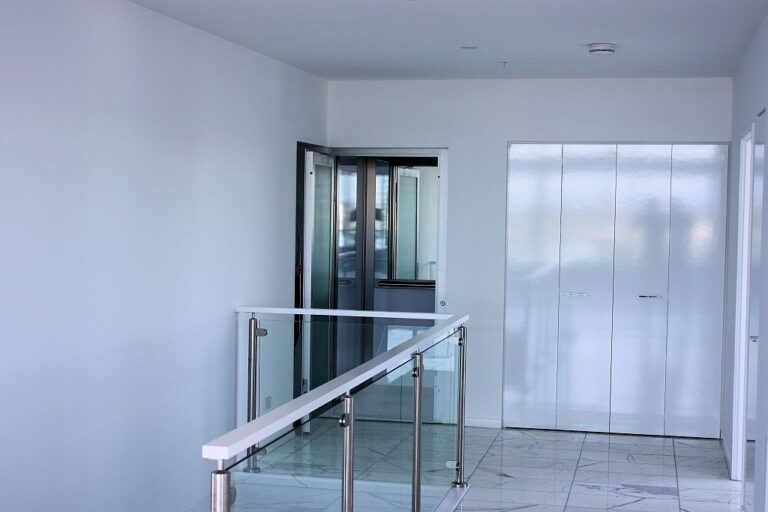 Penthouse landing at Sapphire Towers with a glass balustrade, white cupboards and the ElfoLift door beside the stairwell