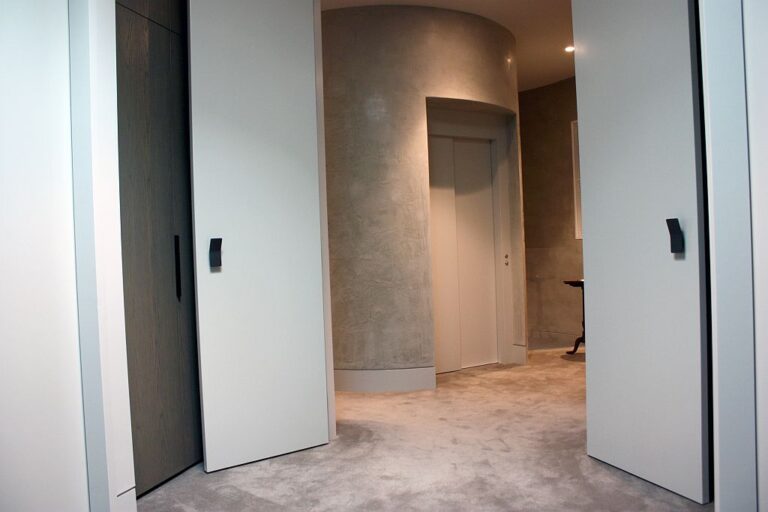 Curved rendered lift shaft seen between two large white doors in an Armadale hallway