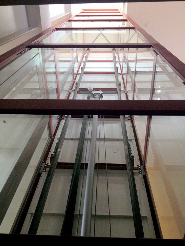 Looking up the glass lift shaft at the steel guides and glass roof