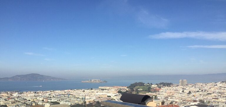 Panoramic view over rooftops and a bay under a clear blue sky in San Francisco