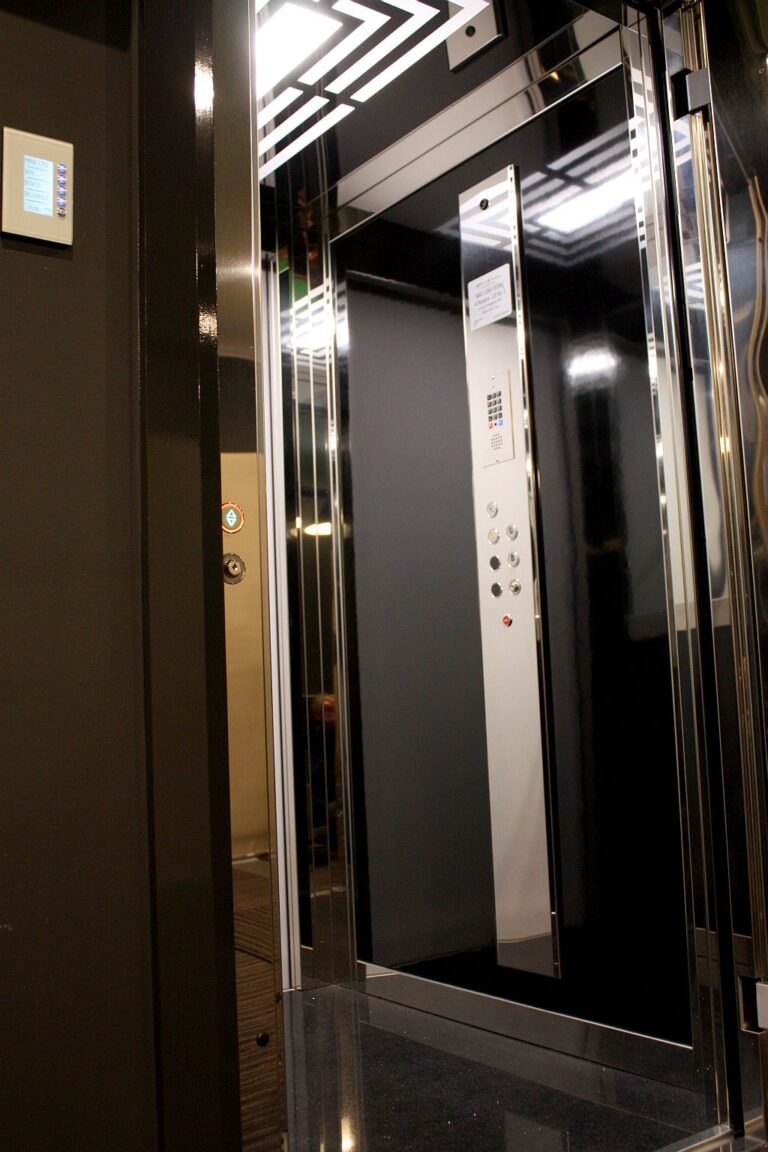 Inside the lift cabin: black panels, a vertical panel with a column of buttons and a patterned ceiling light