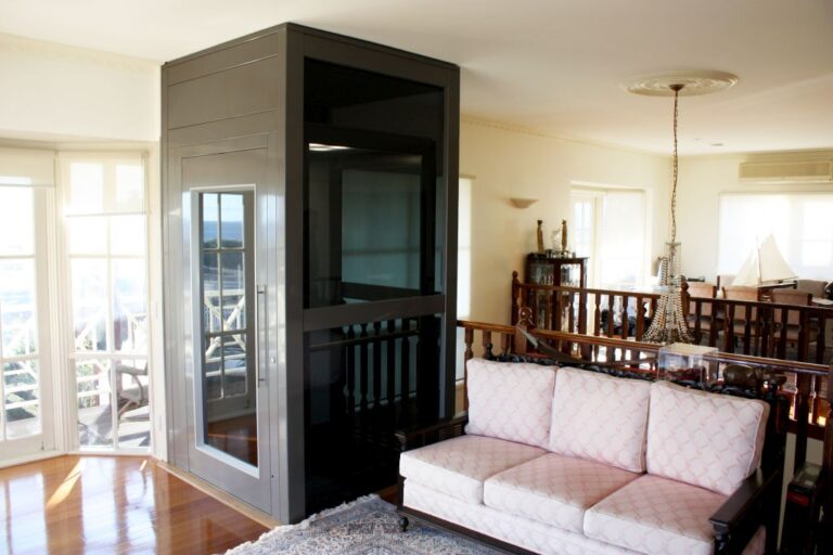 Living room with a grey lift shaft beside a sofa and timber balustrade