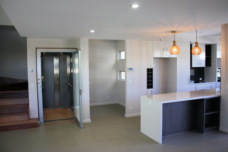 Kitchen and dining area with an open lift door at left and pendant lights