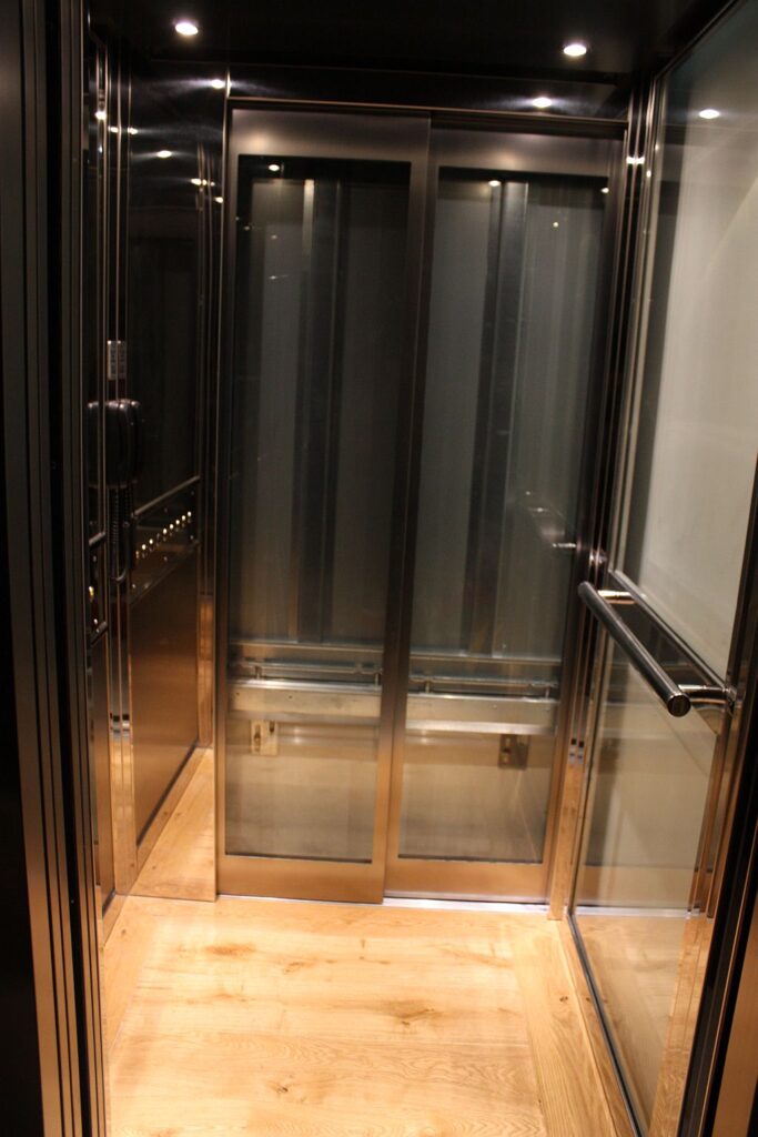 ElfoLift 2 cabin looking out through the open doors, with a stainless steel handrail and LED downlights in the ceiling