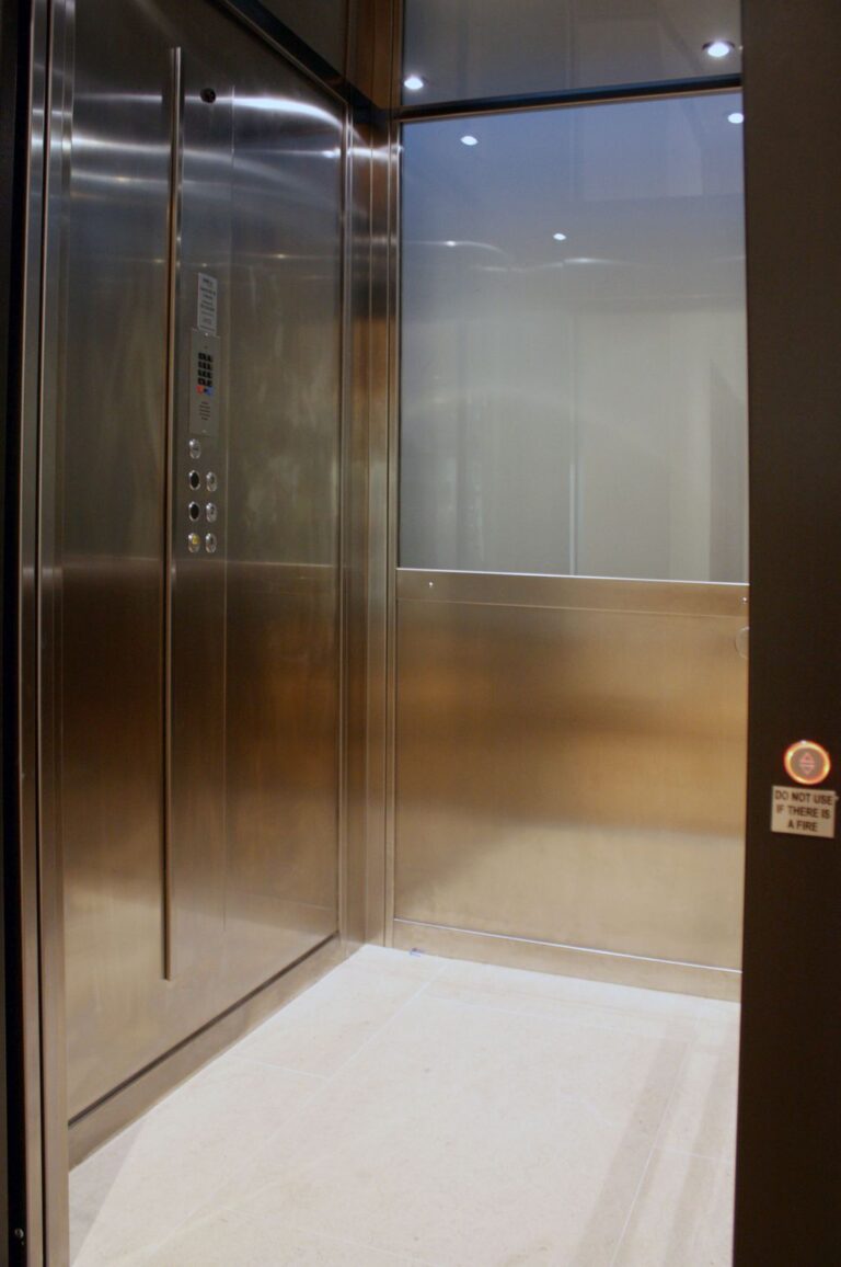 Close view inside the E2 lift car with stainless steel panels and a glass panel