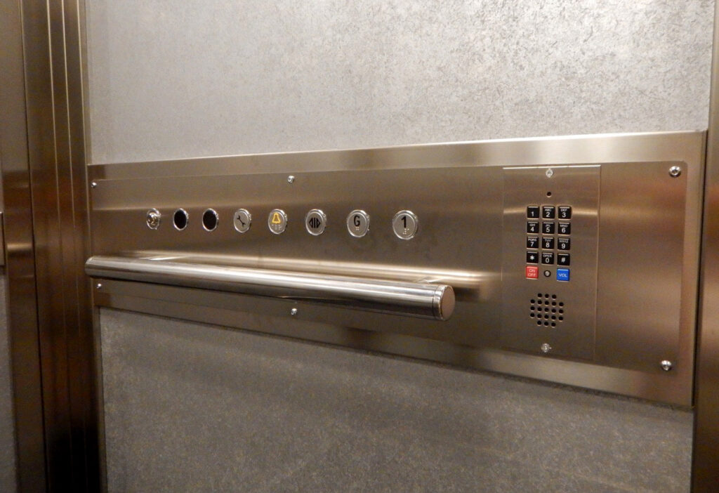 Lift control panel with round buttons, a keypad and a stainless steel handrail