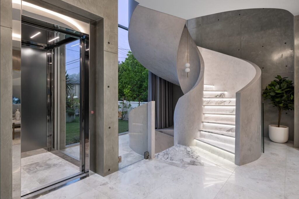 modern foyer with an elevator and a curved staircase
