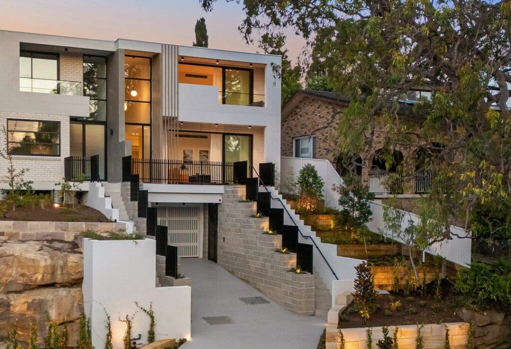 Front of the three-level Connells Point duplex at dusk, with landscaped terraces and stairs up to the entry