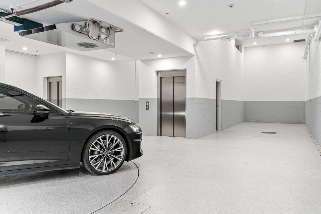 Basement garage with a car on the turntable and the lift doors beside it at the Connells Point duplex